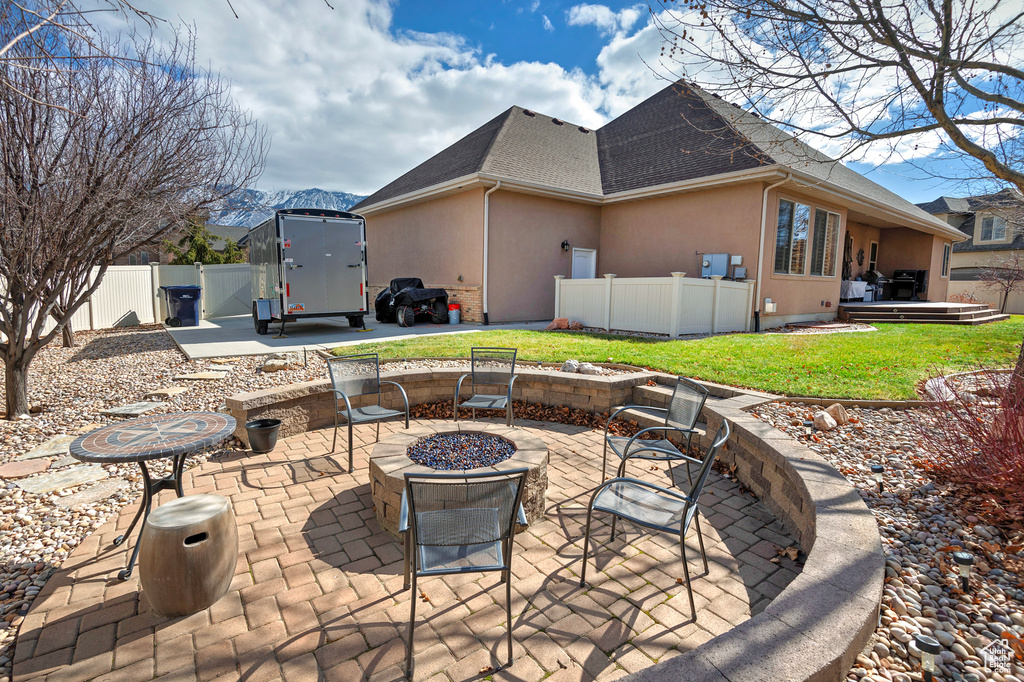 View of patio with a trampoline, an outdoor fire pit, fence, and a mountain view