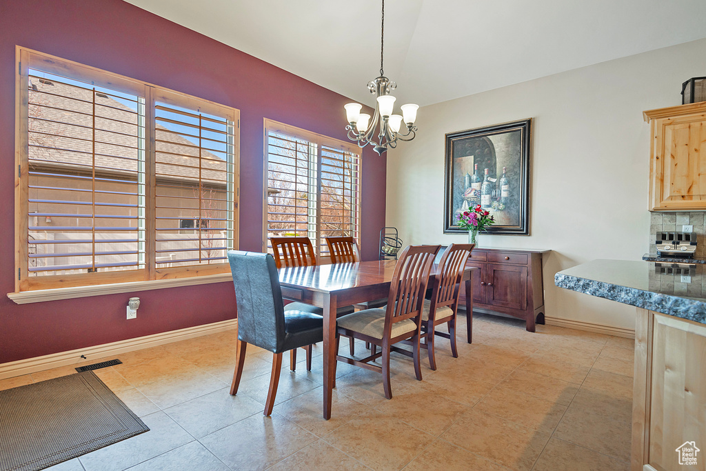 Dining space featuring light tile patterned floors, baseboards, visible vents, and a notable chandelier