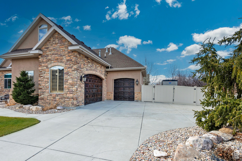 View of front of property featuring a gate, concrete driveway, and stucco siding