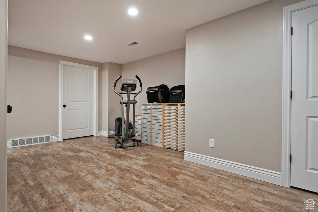 Exercise area with light wood-style flooring, recessed lighting, visible vents, and baseboards