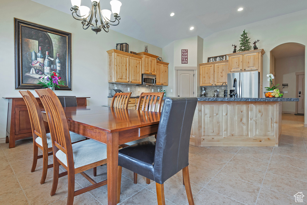 Dining room with arched walkways, light tile patterned floors, recessed lighting, lofted ceiling, and an inviting chandelier