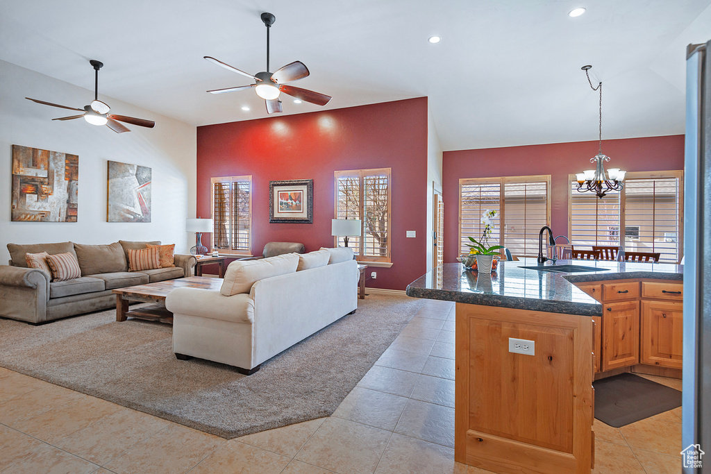 Living area with high vaulted ceiling, recessed lighting, light tile patterned floors, and ceiling fan with notable chandelier