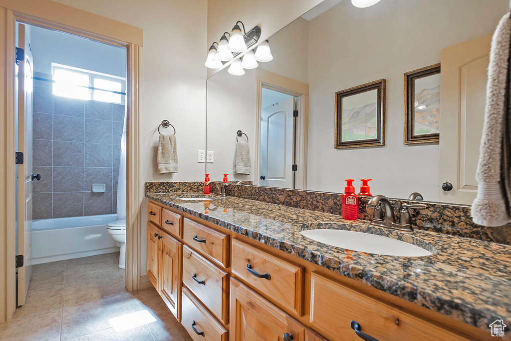 Full bathroom featuring double vanity, a sink, toilet, and tile patterned floors