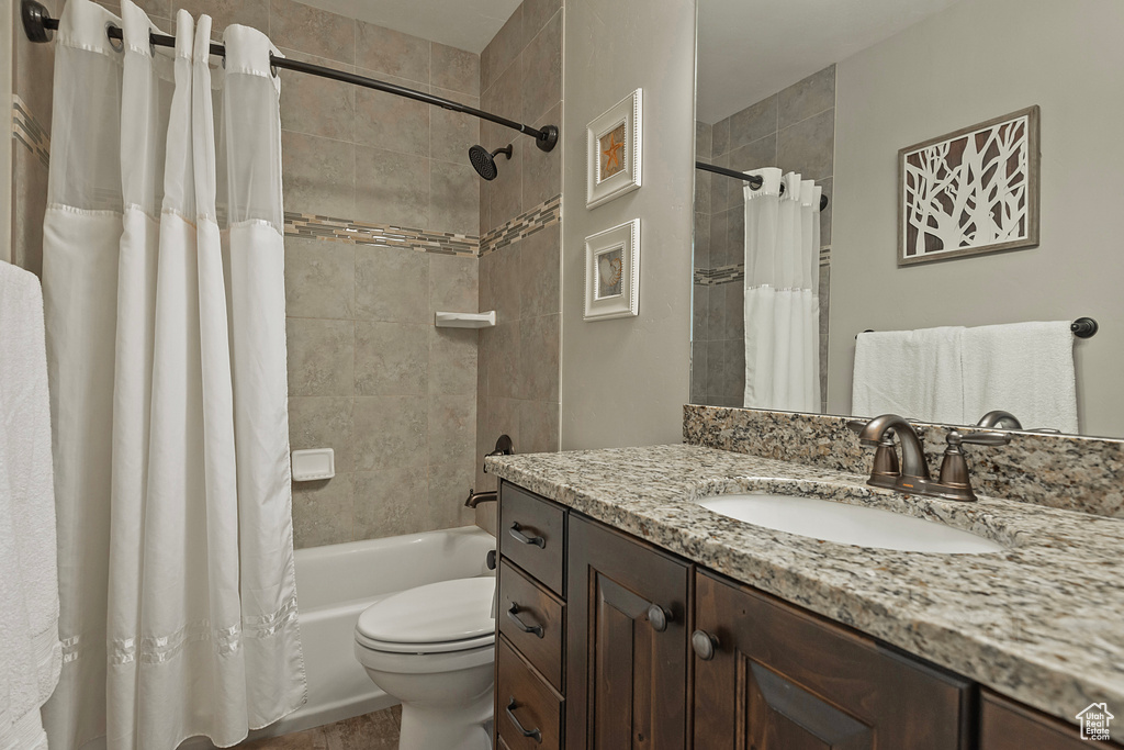 Full bathroom featuring toilet, shower / tub combo with curtain, and vanity