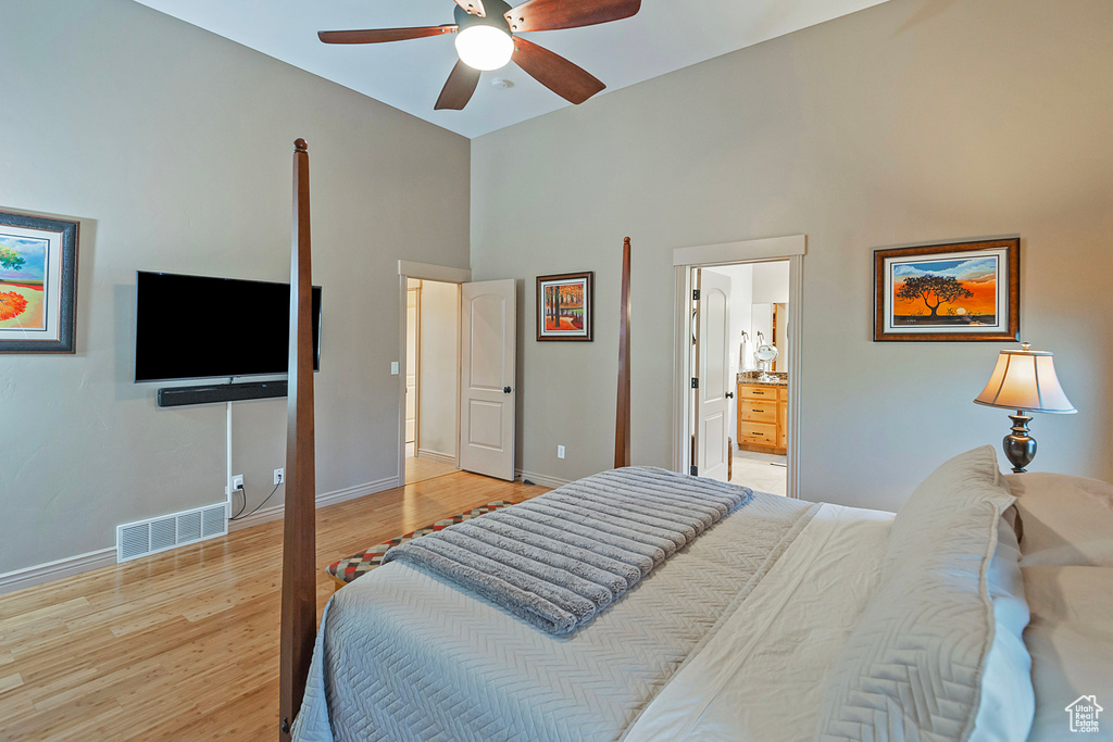 Bedroom featuring baseboards, visible vents, connected bathroom, a towering ceiling, and light wood-style floors