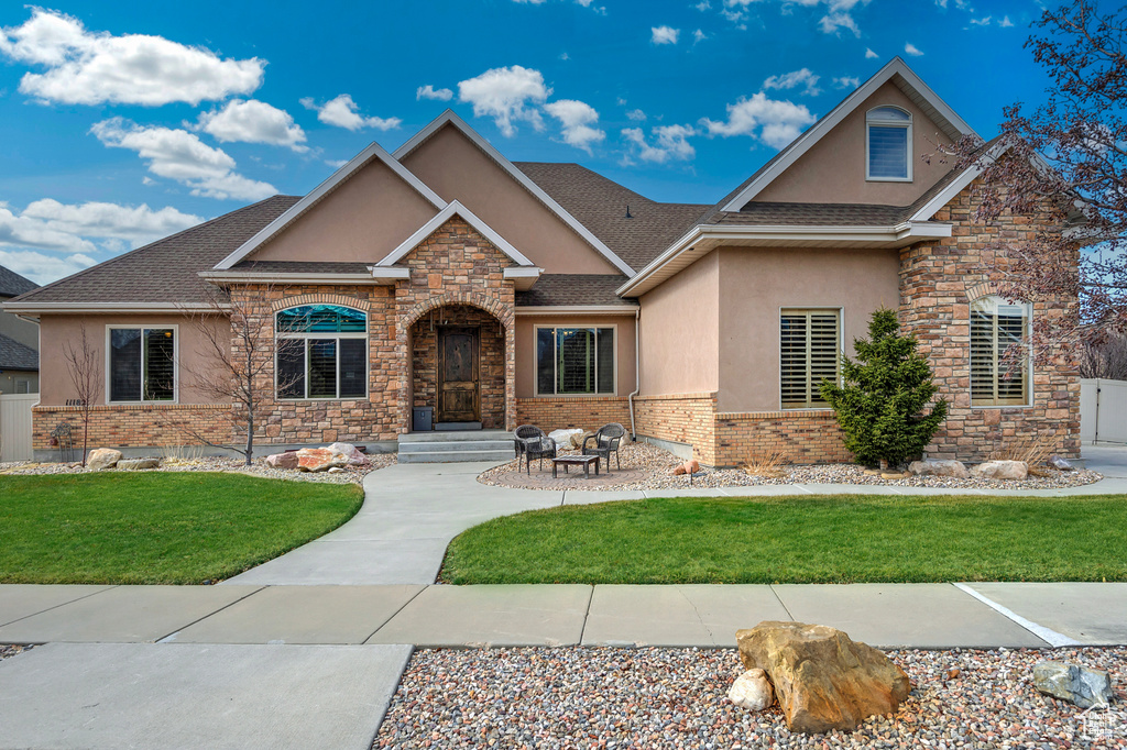 Craftsman-style house featuring a front yard, roof with shingles, brick siding, and stucco siding