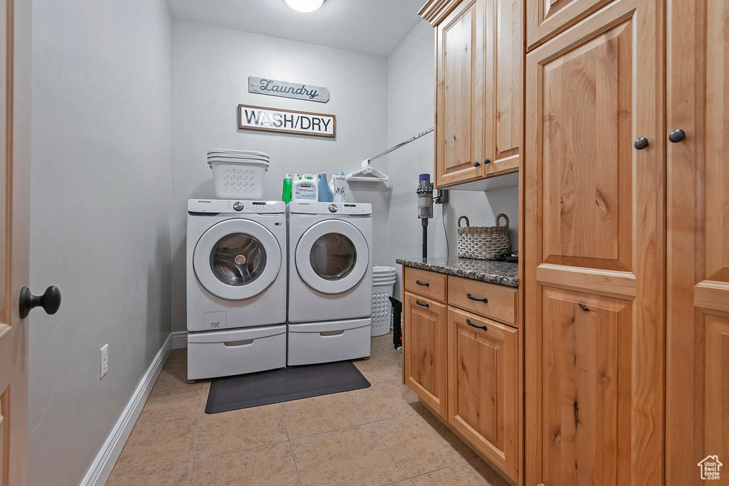 Laundry room featuring light tile patterned floors, cabinet space, baseboards, and separate washer and dryer