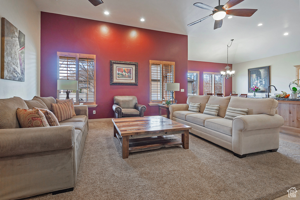 Living room with recessed lighting, a healthy amount of sunlight, light carpet, and ceiling fan with notable chandelier