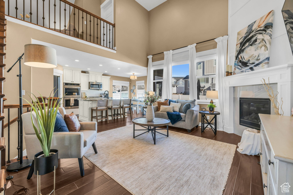 Living area featuring a high ceiling, dark wood finished floors, and a tile fireplace