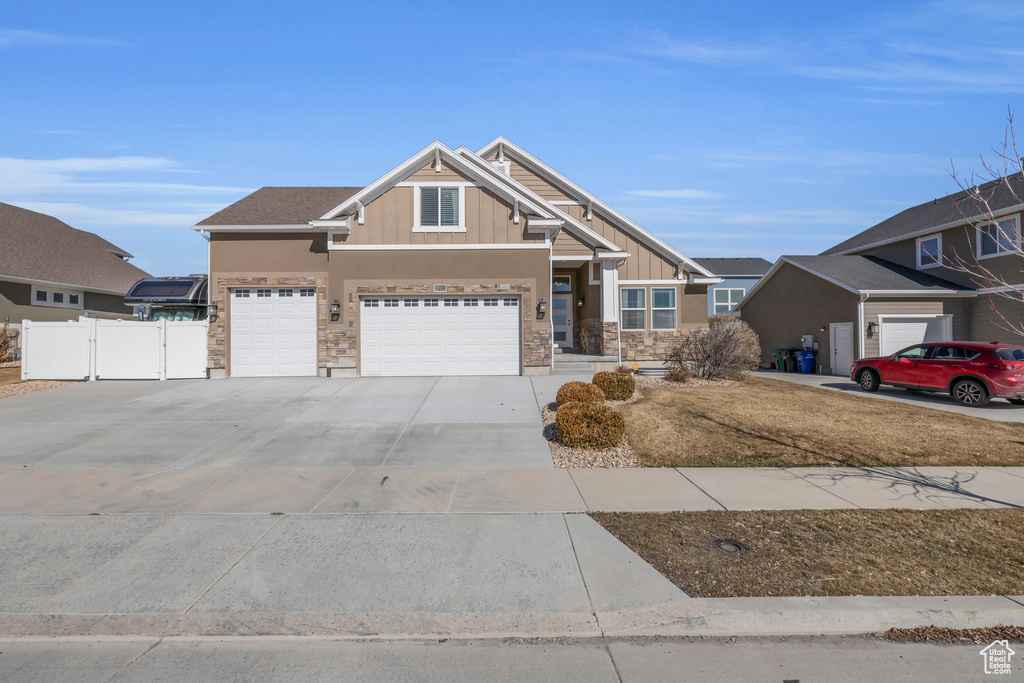 Craftsman house with board and batten siding, a gate, fence, stone siding, and driveway