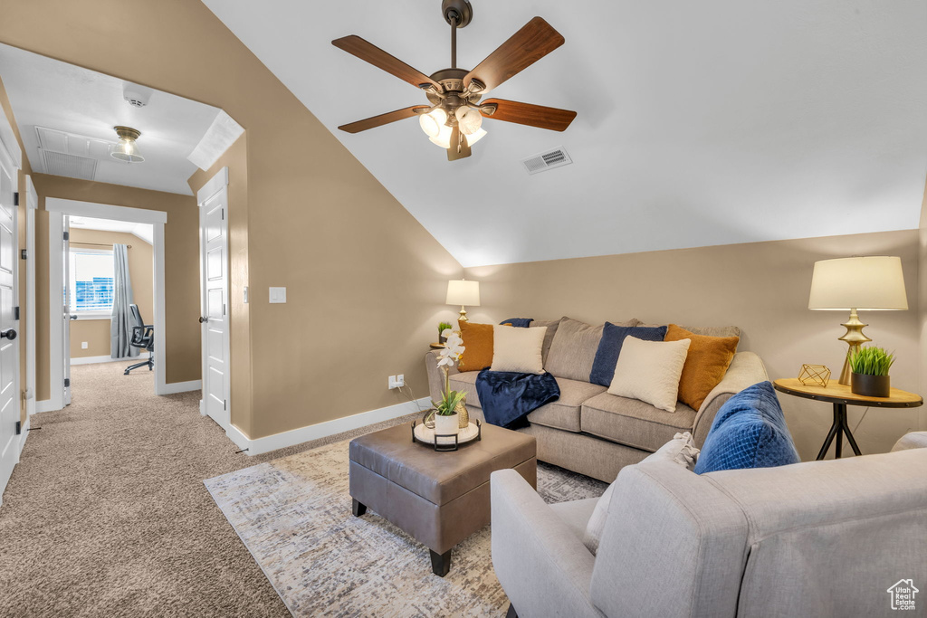 Living area featuring light carpet, a ceiling fan, visible vents, vaulted ceiling, and baseboards