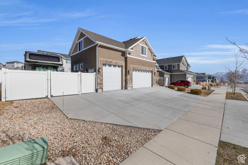 View of home\'s exterior with a garage, concrete driveway, a residential view, a gate, and board and batten siding