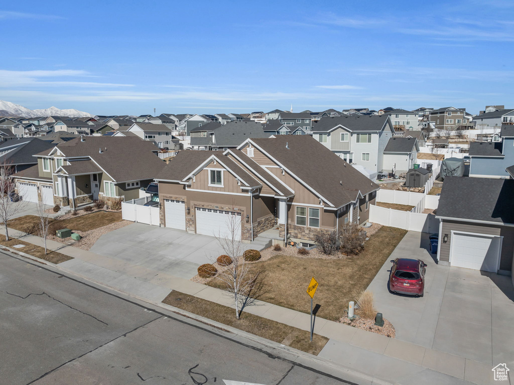 View of front of house with driveway, fence, and a residential view