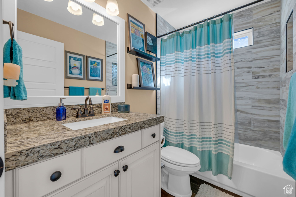 Bathroom with shower / bath combo, vanity, and toilet