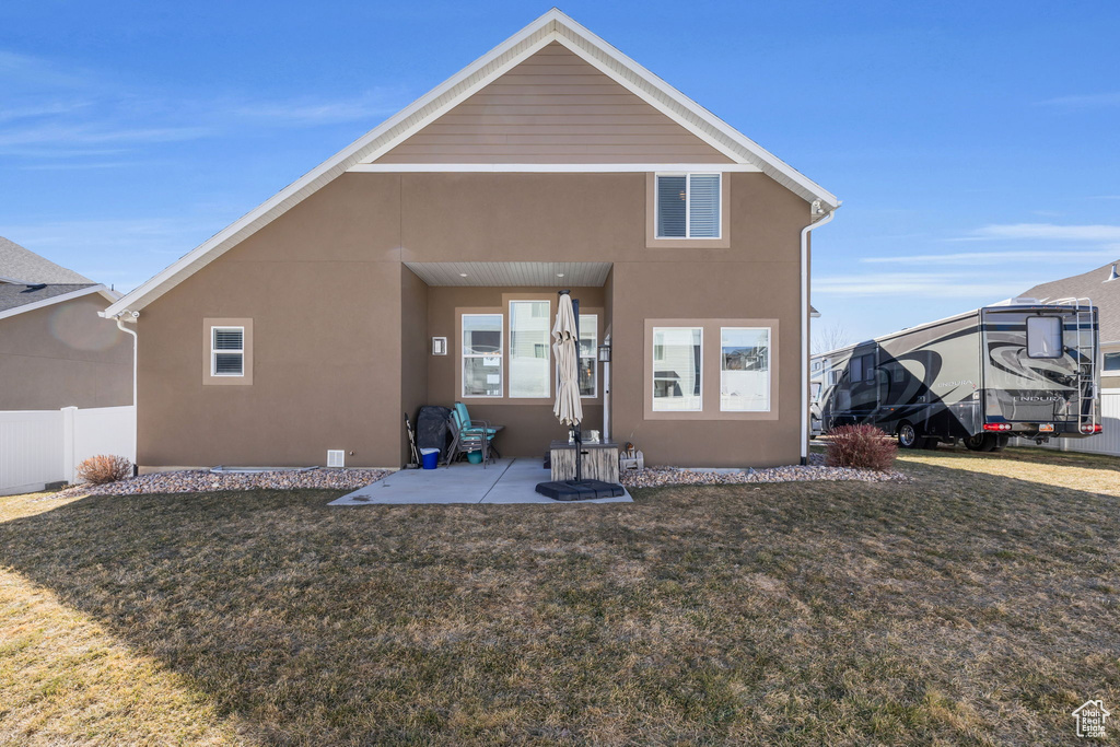 Back of property featuring a patio area, fence, a lawn, and stucco siding