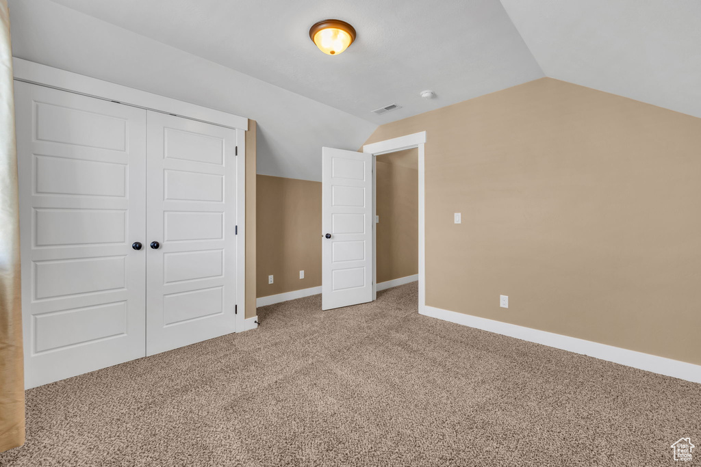 Unfurnished bedroom featuring lofted ceiling, carpet flooring, and baseboards