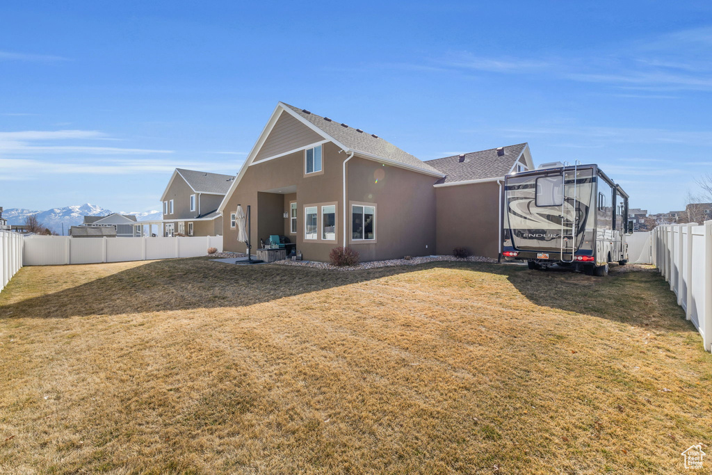 Rear view of property with a yard, a fenced backyard, and stucco siding