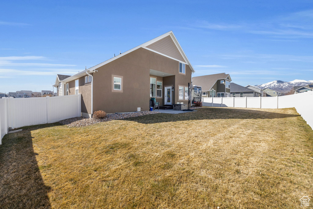 Back of house featuring a lawn, a fenced backyard, a residential view, a patio area, and stucco siding