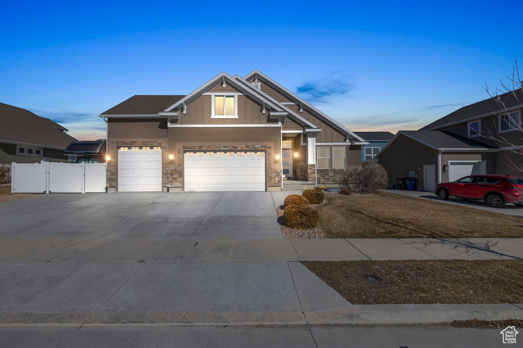 Craftsman house featuring stone siding, a gate, fence, and concrete driveway