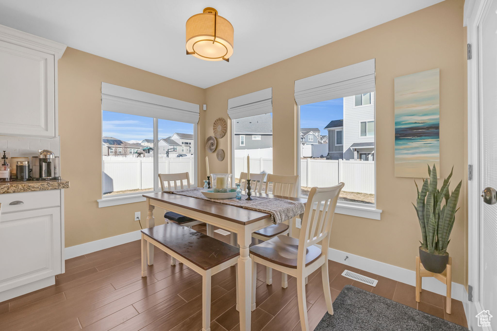 Dining area featuring dark wood-type flooring, visible vents, and baseboards