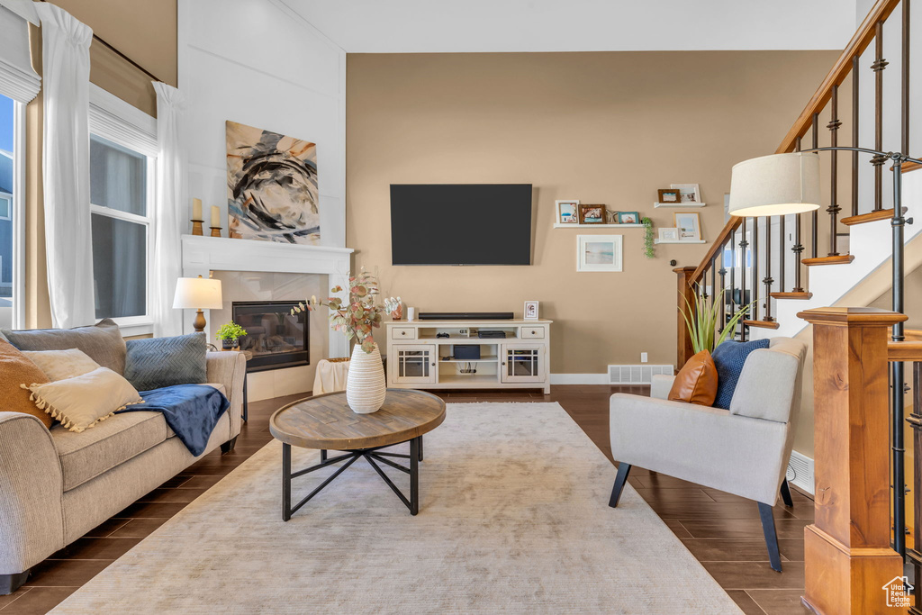 Living area featuring visible vents, wood tiled floor, a tile fireplace, baseboards, and stairs