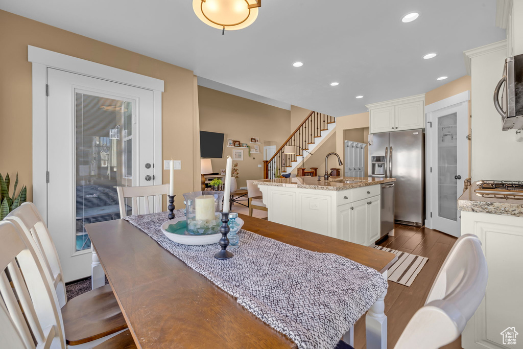 Dining area with dark wood-style floors, recessed lighting, and stairway