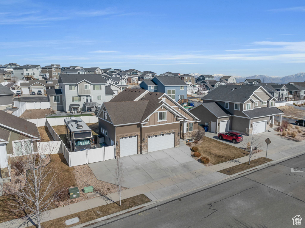 View of front facade featuring concrete driveway, an attached garage, fence, and a residential view