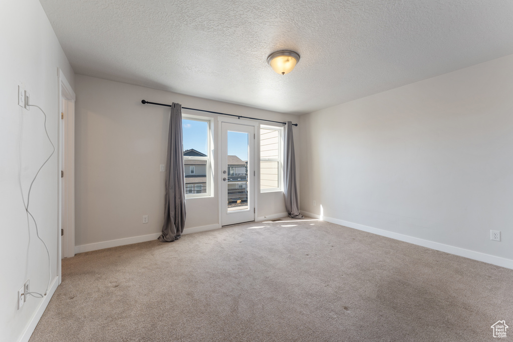 Carpeted empty room featuring baseboards and a textured ceiling