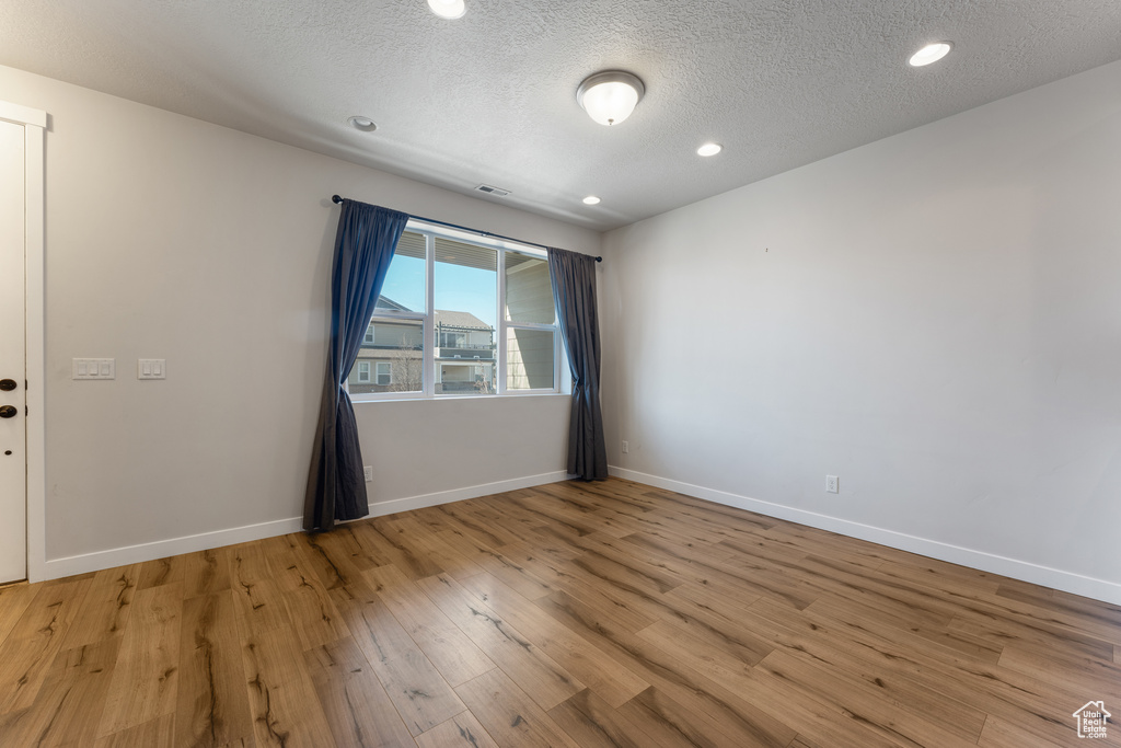 Spare room featuring visible vents, baseboards, a textured ceiling, light wood-style floors, and recessed lighting