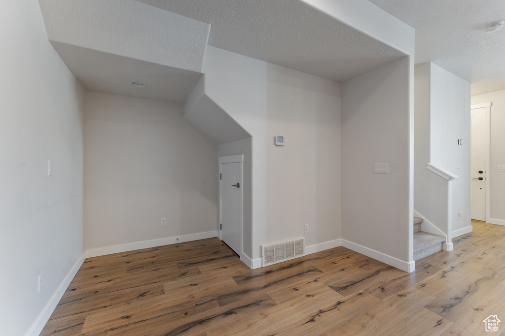 Bonus room featuring wood-type flooring, visible vents, a textured ceiling, baseboards, and stairs