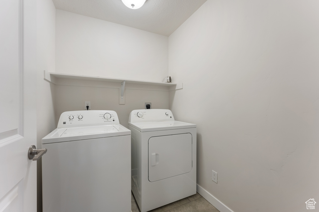 Laundry room with light tile patterned floors, laundry area, independent washer and dryer, and baseboards