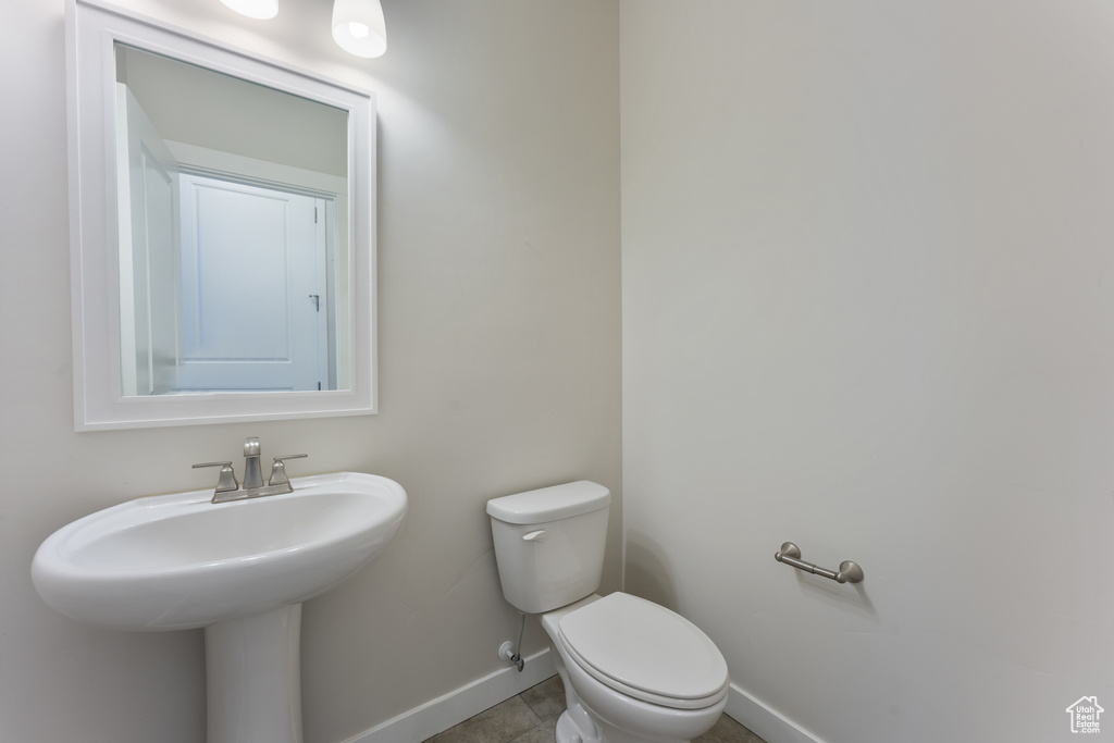 Half bath featuring a sink, tile patterned floors, toilet, and baseboards