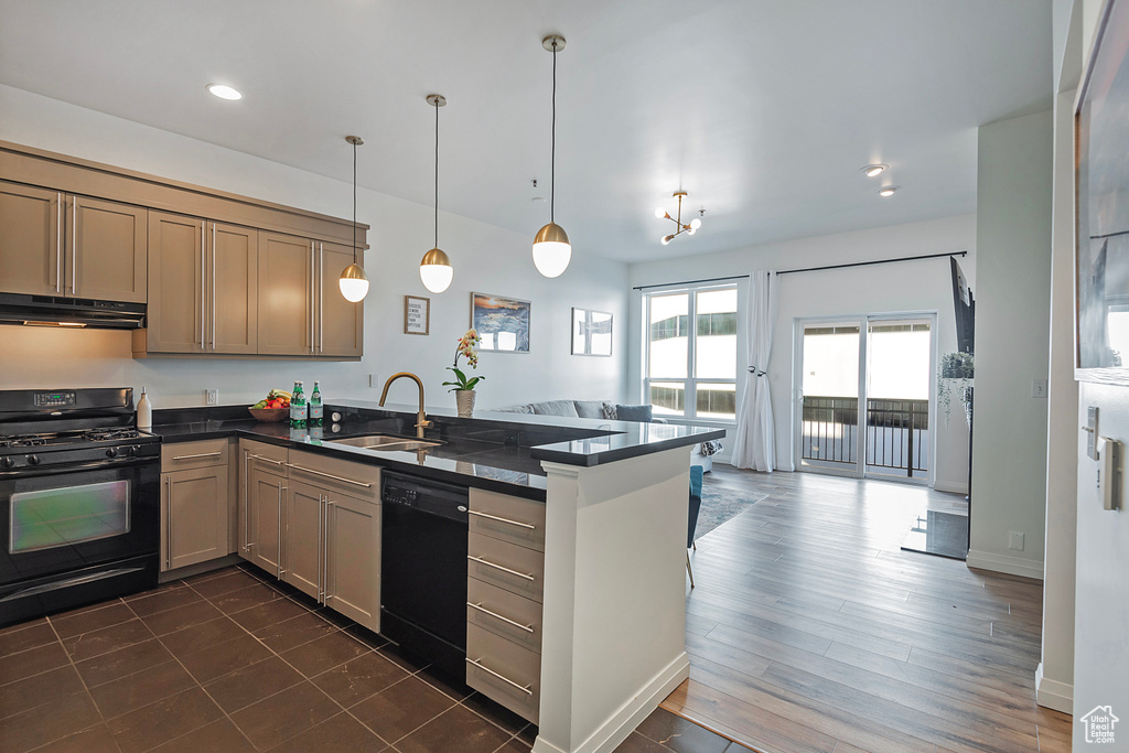 Kitchen featuring under cabinet range hood, a peninsula, a sink, black appliances, and dark countertops