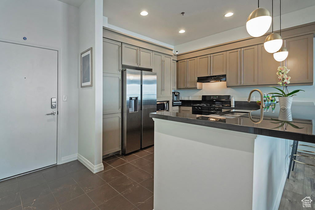 Kitchen with range hood, stainless steel appliances, dark countertops, a sink, and a peninsula