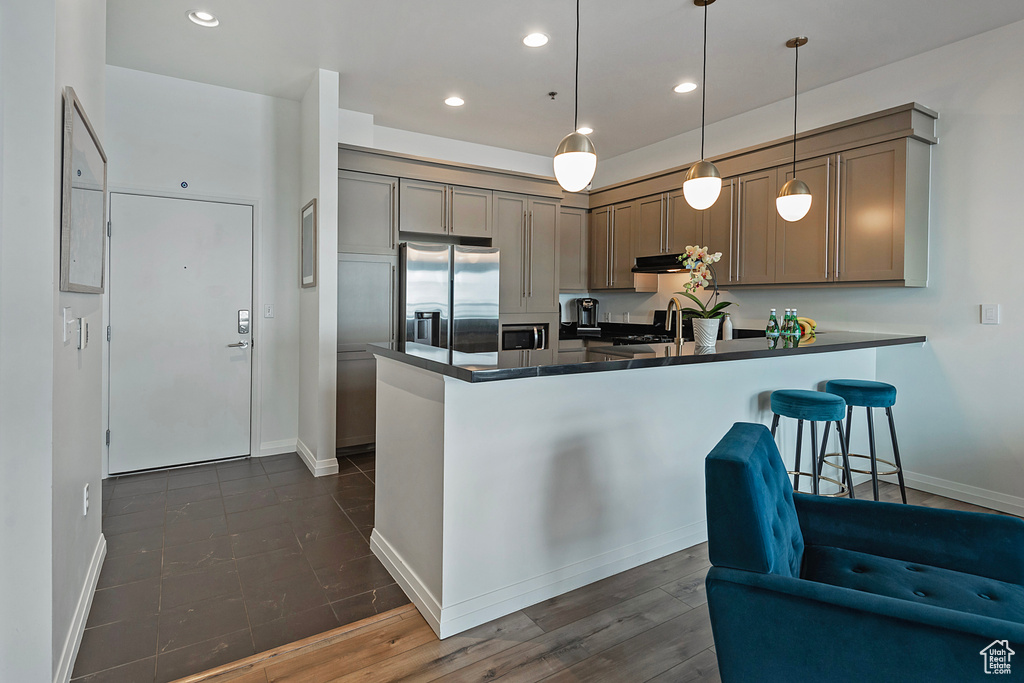 Kitchen with a peninsula, dark countertops, stainless steel fridge, and recessed lighting