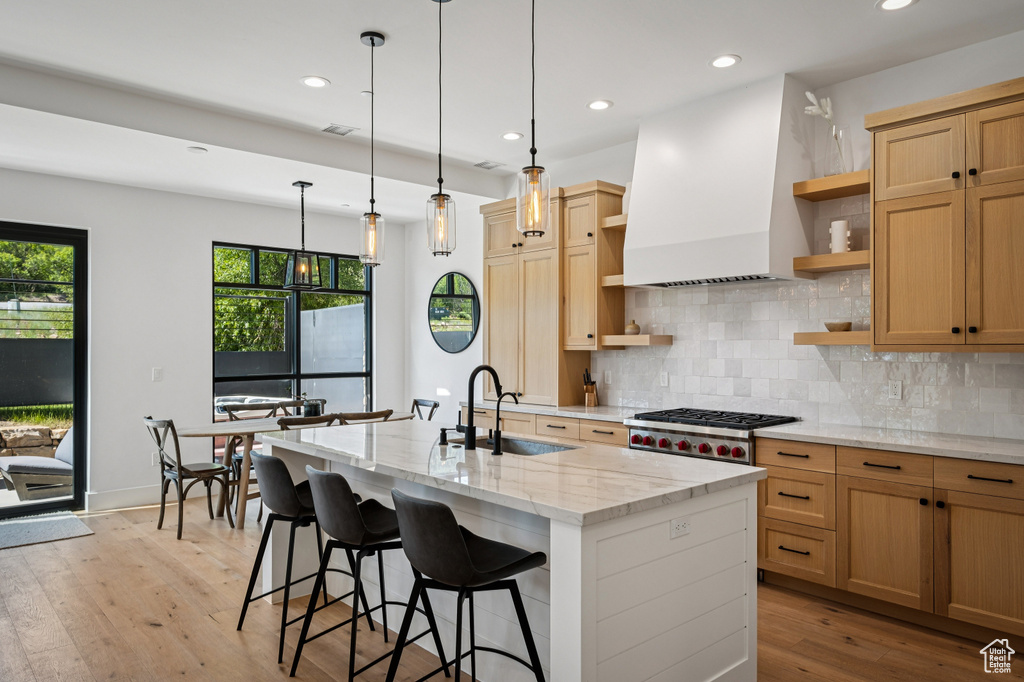 Kitchen with open shelves, premium range hood, a center island with sink, decorative backsplash, and recessed lighting