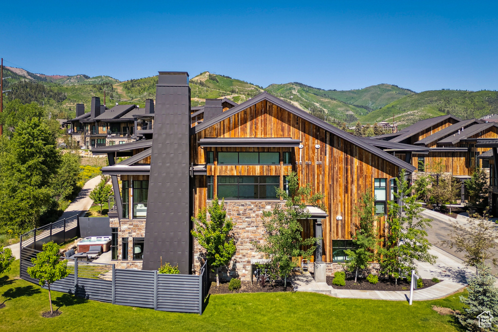 Back of house featuring a lawn, a chimney, and a mountain view