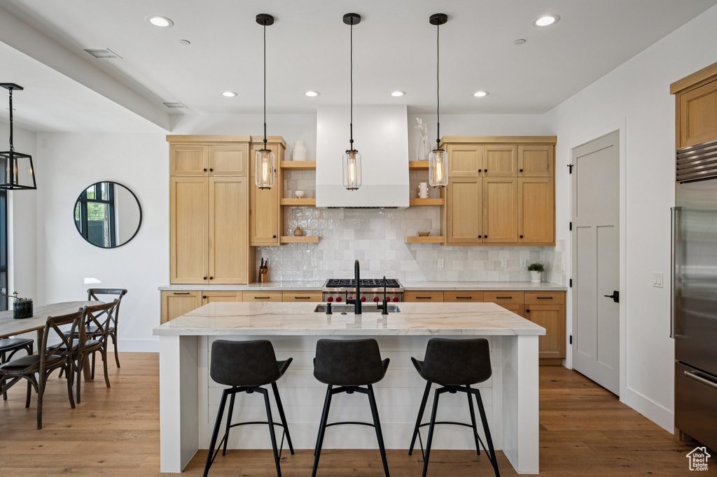 Kitchen with open shelves, high quality fridge, light wood-type flooring, decorative backsplash, and recessed lighting