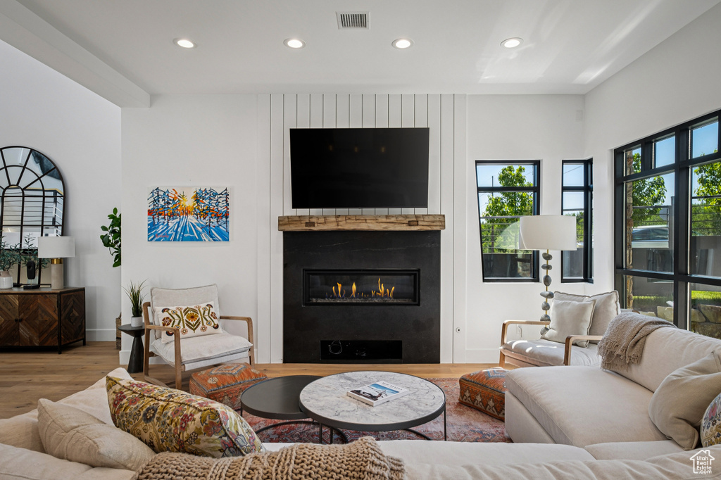 Living room with wood finished floors, a fireplace, and recessed lighting