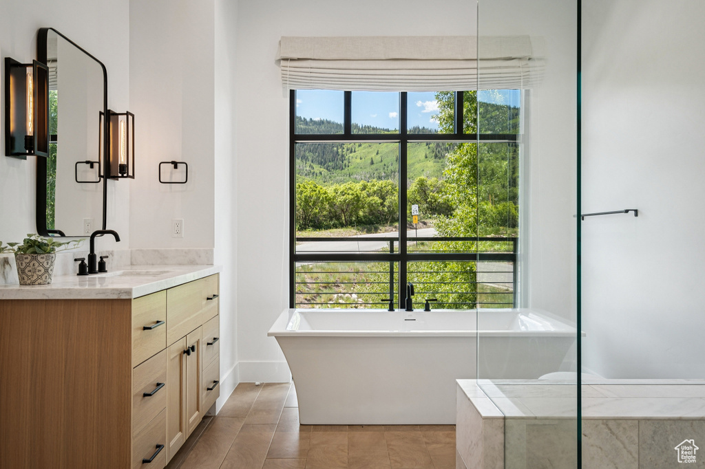 Full bath featuring vanity, a freestanding tub, and tile patterned flooring
