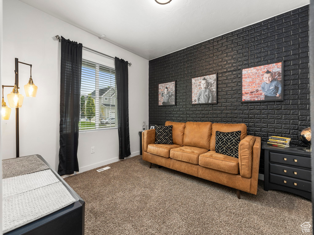 Living area featuring baseboards, visible vents, brick wall, an accent wall, and carpet flooring