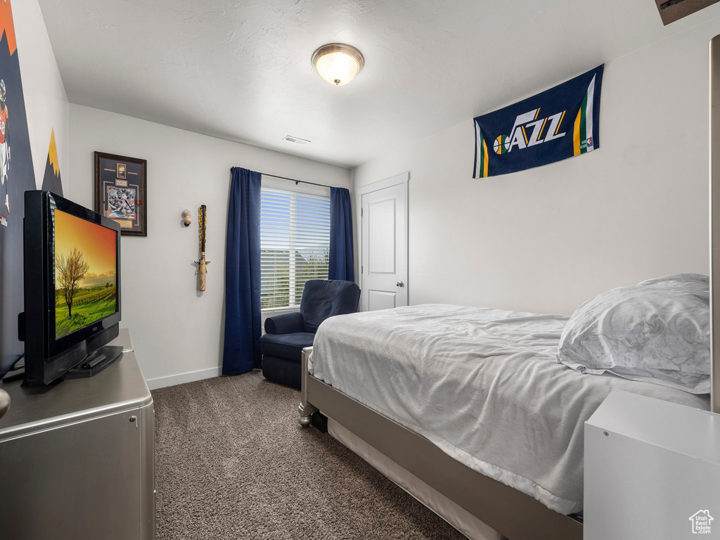 Bedroom with visible vents, dark carpet, and baseboards