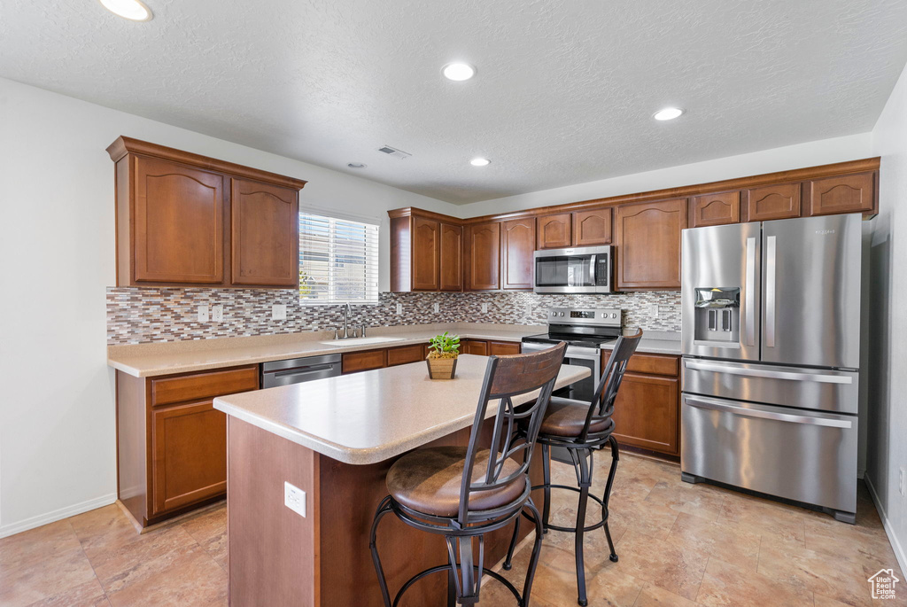 Kitchen featuring stainless steel appliances, a sink, visible vents, light countertops, and backsplash