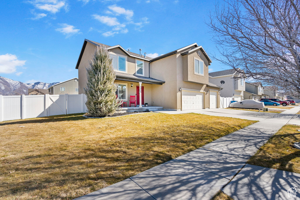 View of front facade featuring a garage, concrete driveway, fence, and stucco siding