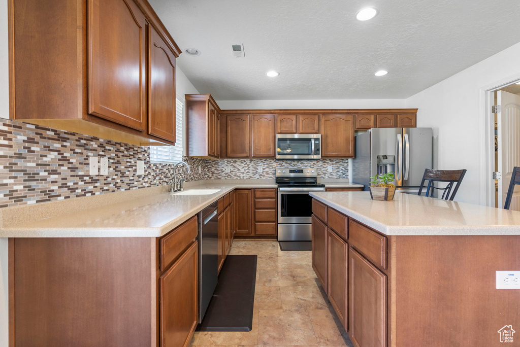 Kitchen featuring stainless steel appliances, visible vents, decorative backsplash, a sink, and a kitchen island