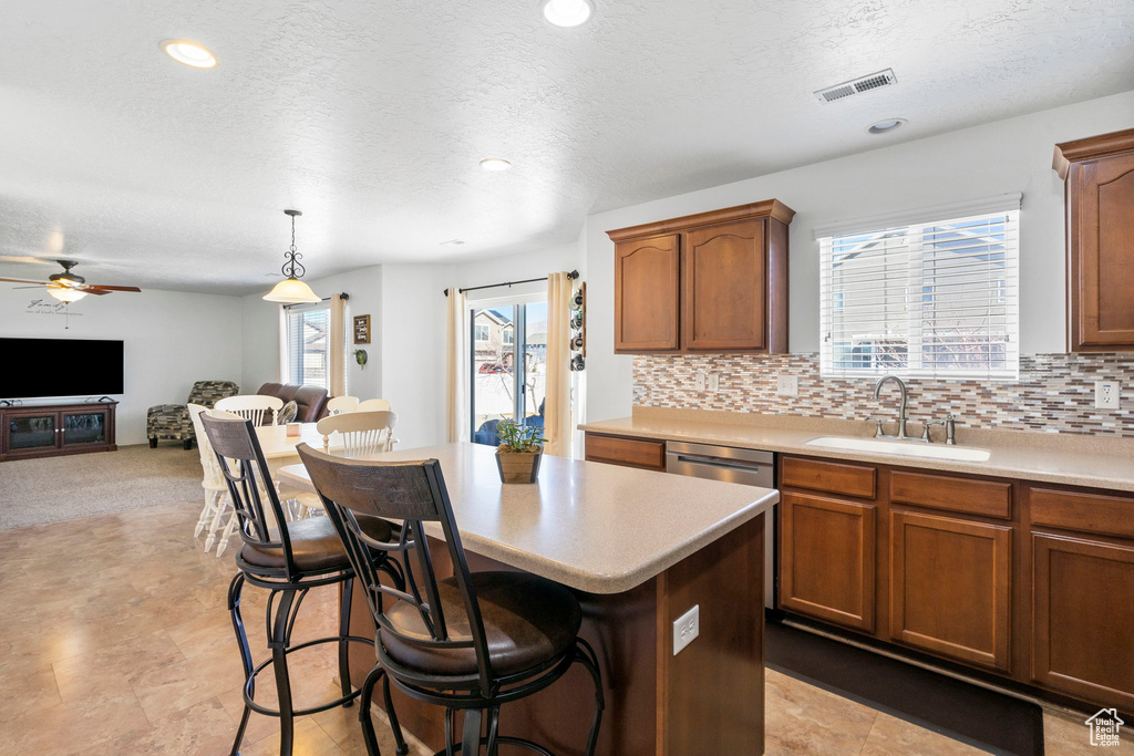 Kitchen featuring light countertops, visible vents, backsplash, open floor plan, and a sink