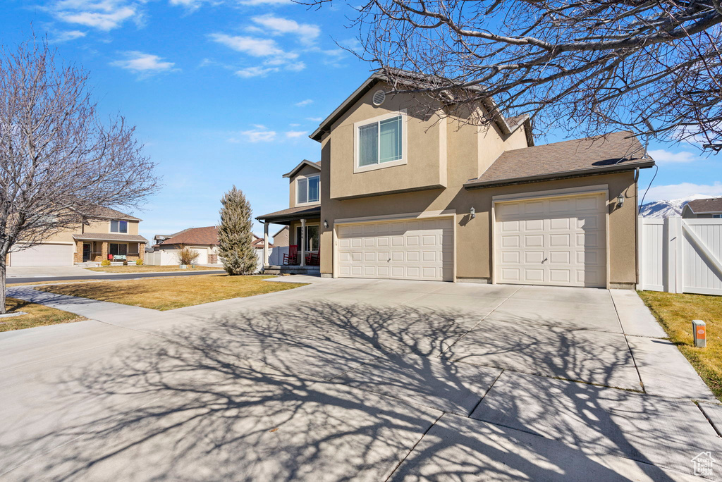 Traditional-style house with driveway, a gate, fence, a front lawn, and stucco siding