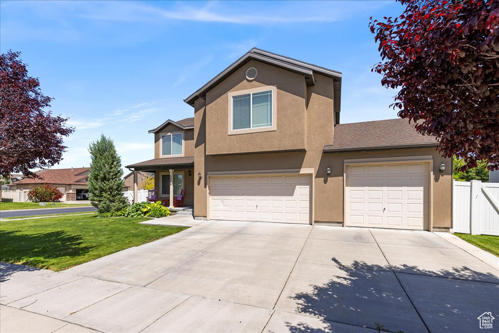 Traditional-style home with driveway, stucco siding, and a garage
