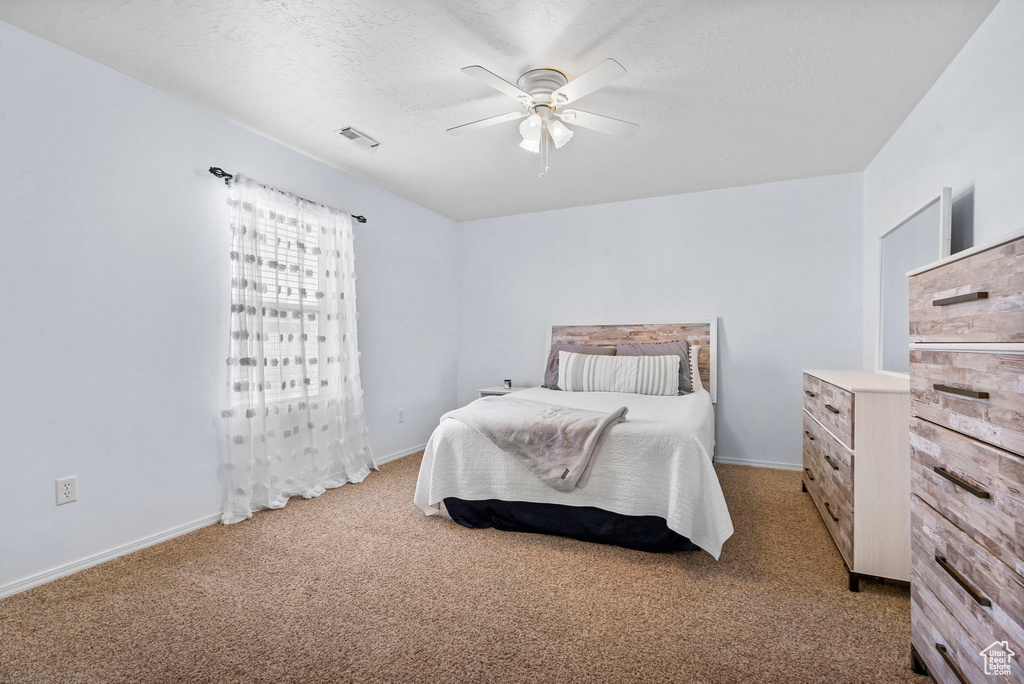 Carpeted bedroom with a ceiling fan, baseboards, visible vents, and a textured ceiling