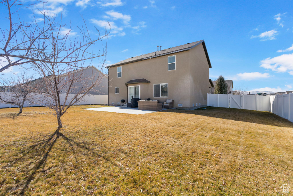 Back of house with a fenced backyard, an outdoor living space, a yard, stucco siding, and a patio area